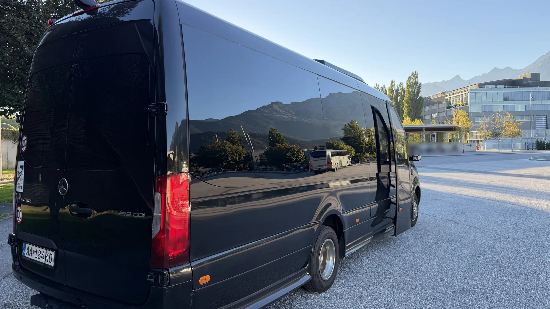 Black SprinterHire Mercedes Sprinter minibus parked below the Alps