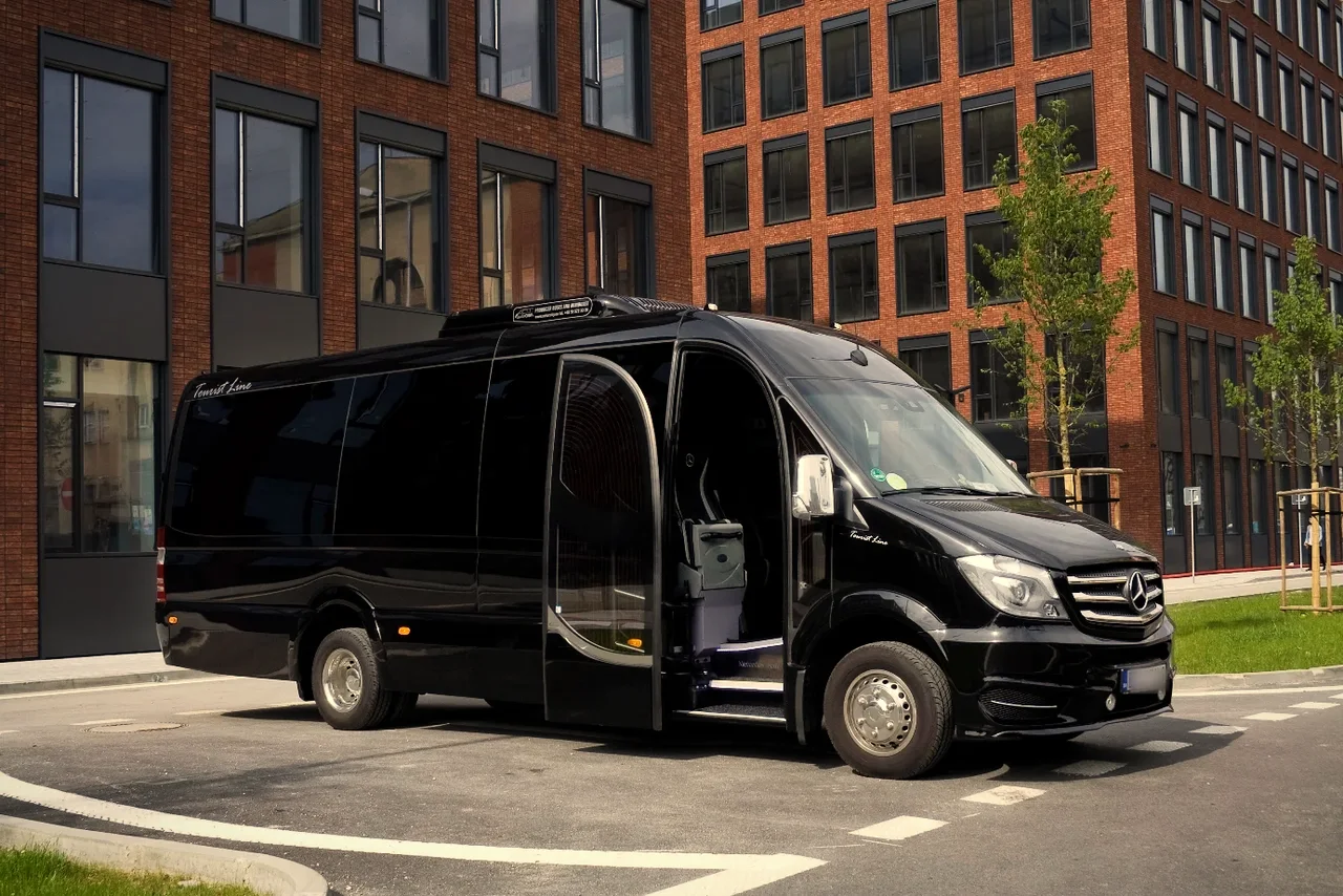 Black SprinterHire Mercedes Sprinter minibus with open passenger door, ready for a tour group