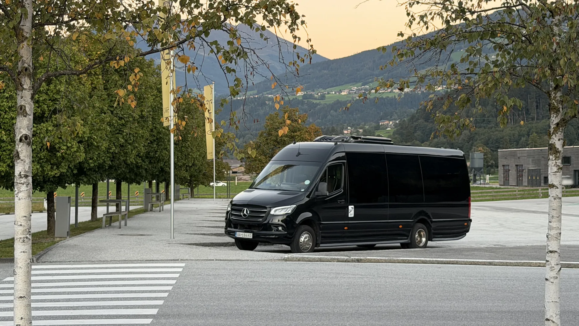Black SprinterHire Mercedes Sprinter minibus parked below the Alps